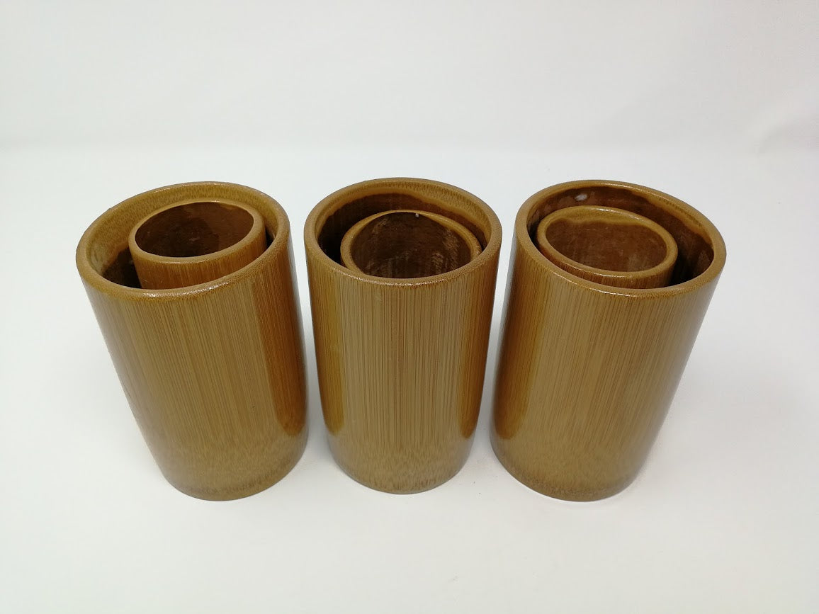 Six brown cylindrical bamboo cups on a white background