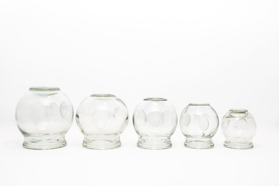 Set of five clear glass tumblers of different sizes on a white background