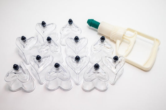 Set of heart shaped clear cupping devices with a pump on a white background