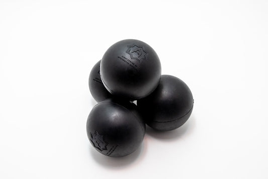 Four black massage balls stacked on a white background