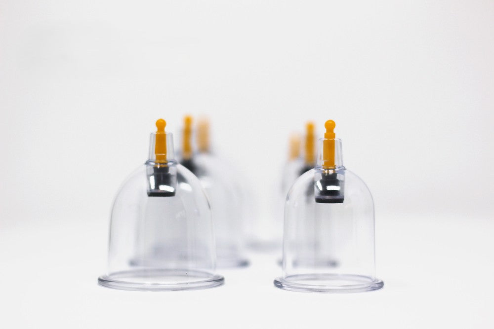 Clear glass cupping devices with black suction cups on a white background