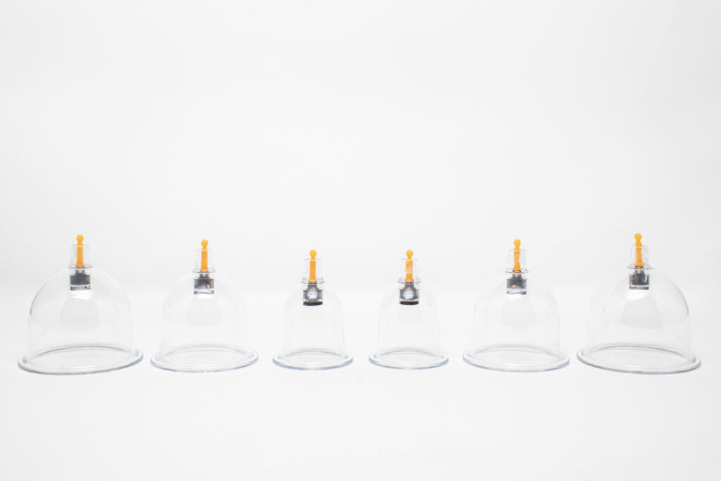 Set of six clear glass bottles with yellow nozzles on a white background