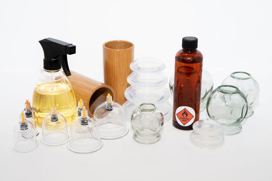 Collection of cupping therapy tools including glass cups, a spray bottle, and a wooden container on a white background.