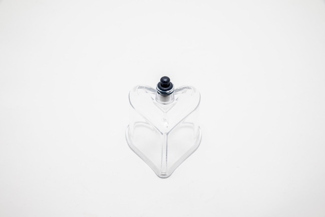 Clear glass heart-shaped object with a black cap on a white background