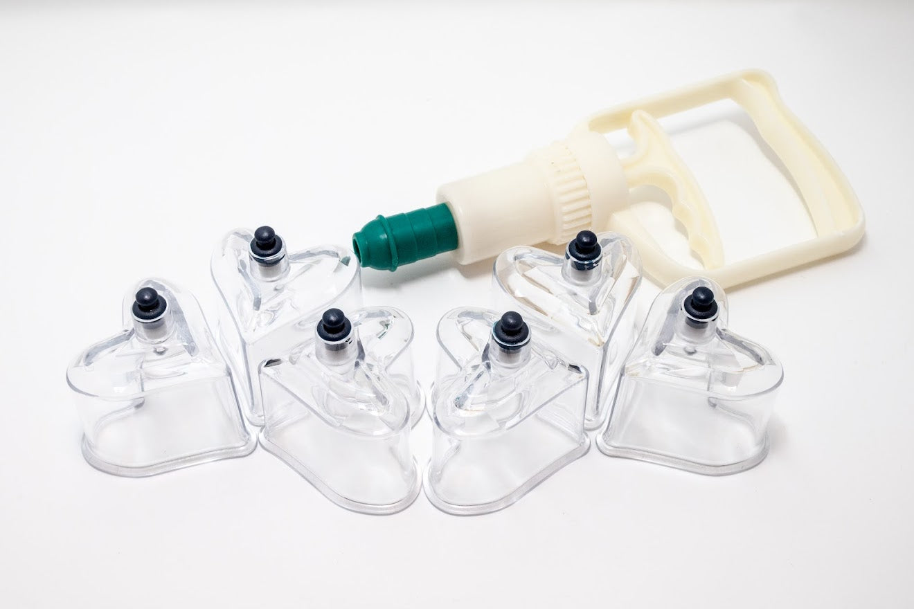 Set of 6 clear heart-shaped cupping therapy devices with a pump on a white background